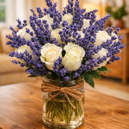 White roses and purple lavender in a glass jar vase