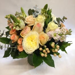 Bouquet of cream and peach roses with pale pink flowers in a vase