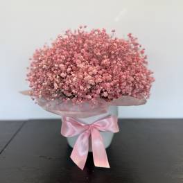 Pink baby's breath bouquet in a white container with a satin ribbon