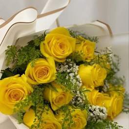 Bouquet of yellow roses with white filler flowers in white wrapping