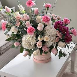Pink and white roses with hydrangeas and orchids in a round box