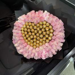 Heart-shaped bouquet of pink roses with gold-wrapped chocolates in the center
