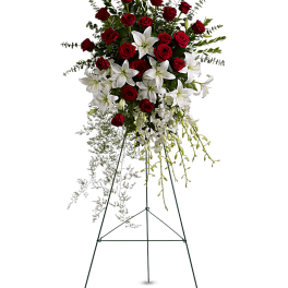 Standing floral spray with red roses and white lilies on a metal easel