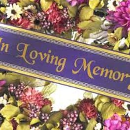 Purple memorial ribbon over a colorful floral wreath