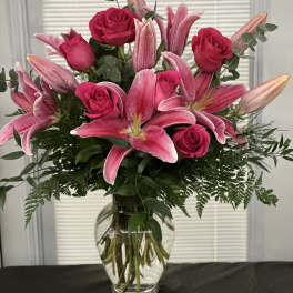 Pink roses and lilies arranged in a clear glass vase