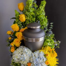 Funeral urn surrounded by yellow roses, hydrangeas, and chrysanthemums
