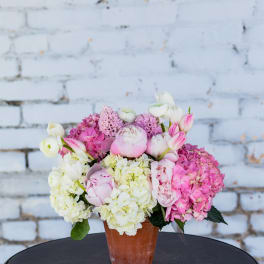 Pink and white flowers arranged in a terracotta pot