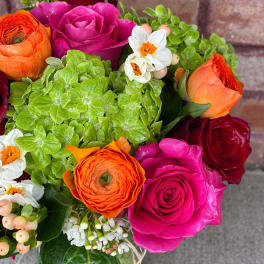Bouquet of pink, red, and orange roses with green hydrangeas and small white flowers
