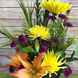 Orange lilies and yellow chrysanthemums in a black vase