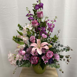 Tall pink and purple floral arrangement in a green vase