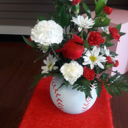 Red and white floral arrangement in a round white vase