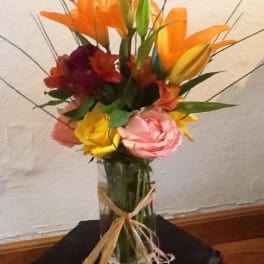 Colorful bouquet of lilies and roses in a glass vase