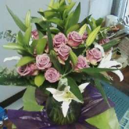 Bouquet of pink roses and white lilies wrapped in purple paper