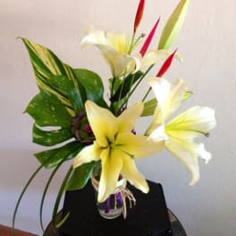 Arrangement of white and yellow lilies in a clear glass vase