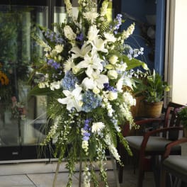 Tall white and blue floral standing spray on a tripod easel