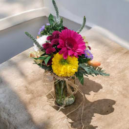 Mixed bouquet in a glass vase with bright pink and yellow blooms