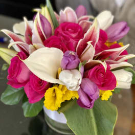 Bouquet of pink roses, white calla lilies, and purple tulips in a vase