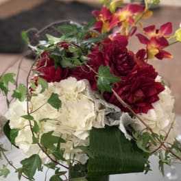 Bouquet of red and white flowers with trailing ivy in a green vase