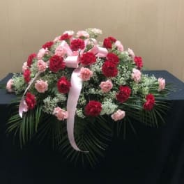 Pink and red carnation arrangement with a ribbon on a table