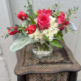 Pink roses and red tulips in a clear glass vase