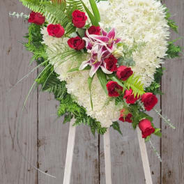 Heart-shaped floral spray with red roses and white blooms on a stand