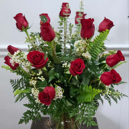 Red roses arranged in a clear glass vase with white filler flowers