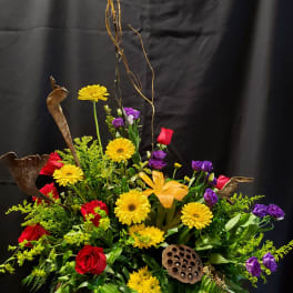 Large mixed floral arrangement with red roses, yellow daisies, and purple blooms