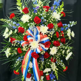 Large standing floral spray with red roses, white daisies, and blue flowers