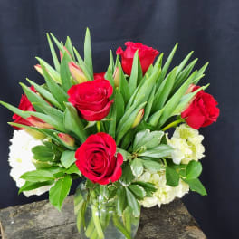 Red roses and white flowers arranged in a glass vase