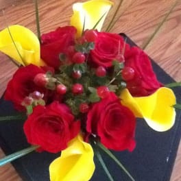 Red roses with yellow calla lilies in a black square vase