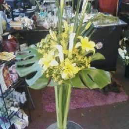 Tall yellow and white floral arrangement in a clear glass vase
