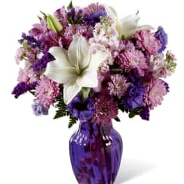 Purple and pink mixed bouquet with white lilies in a purple vase