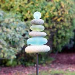 Stacked smooth stones on a metal stake in a garden.