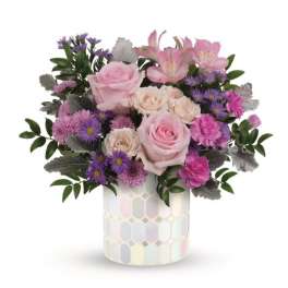 Pink roses and purple flowers in a patterned ceramic vase