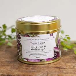 Gold tin candle labeled Wild Fig & Mulberry on a wooden surface