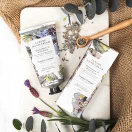 Two floral hand cream tubes with dried lavender and eucalyptus on a tray