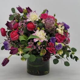 Lush arrangement of pink, purple and white mixed flowers in a clear glass vase