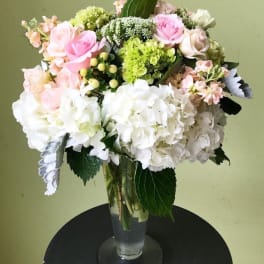 Bouquet of pink, white, and green flowers in a clear glass vase