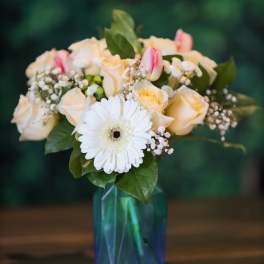 Bouquet of cream roses, pink tulips, and a white gerbera in a blue vase