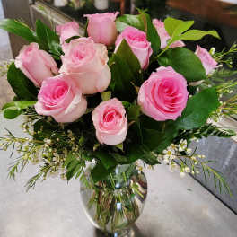 Pink roses arranged in a clear glass vase with small white filler flowers