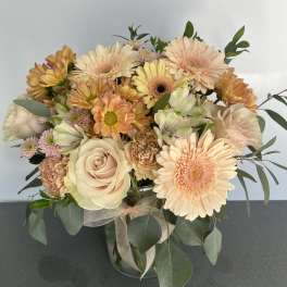 Peach and cream bouquet with roses, gerbera daisies, and chrysanthemums in a glass vase