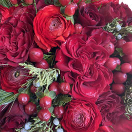 Close-up bouquet of red roses and ranunculus with berry accents