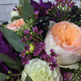 Peach and white roses with purple accent flowers in a bouquet