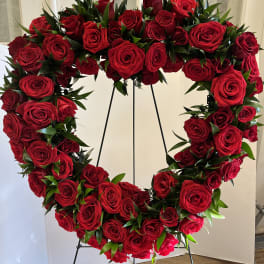 Heart-shaped wreath of red roses on a black stand