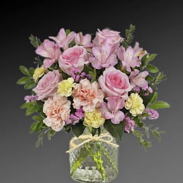 Pink roses and mixed pastel flowers in a clear glass vase