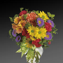 Colorful mixed bouquet in a clear glass vase with a green polka-dot ribbon