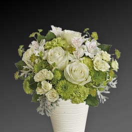 White and green floral arrangement in a ribbed white vase