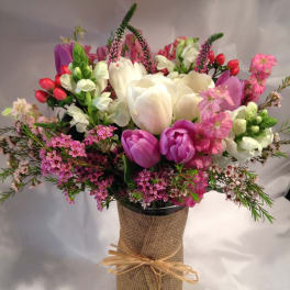 Bouquet of pink, white, and purple flowers in a burlap-wrapped vase