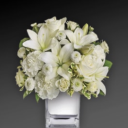 White floral arrangement in a clear square vase