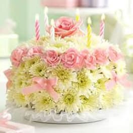 Pink roses and white daisies arranged as a cake with striped candles